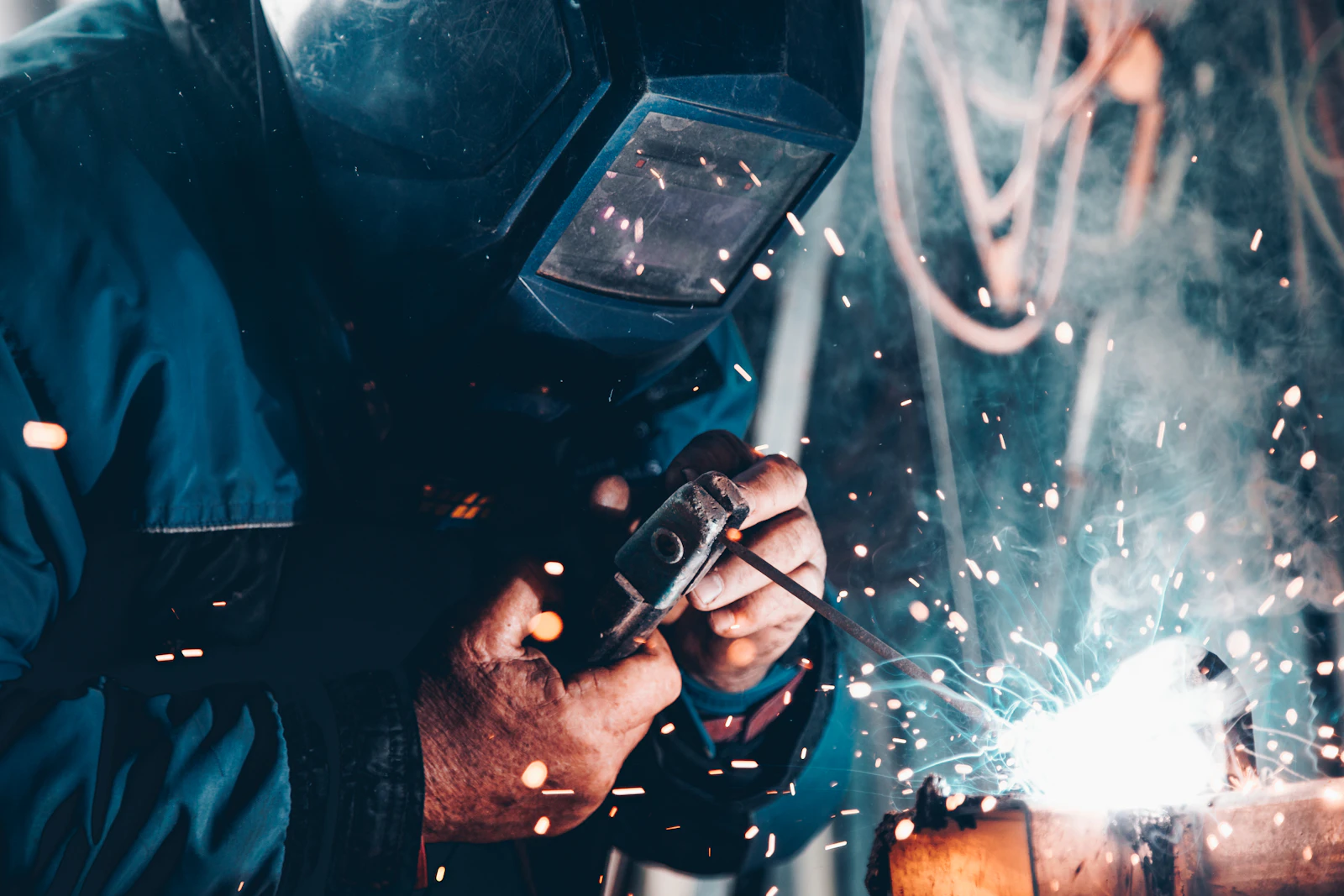 Welder at work amid sparks in a fabrication shop