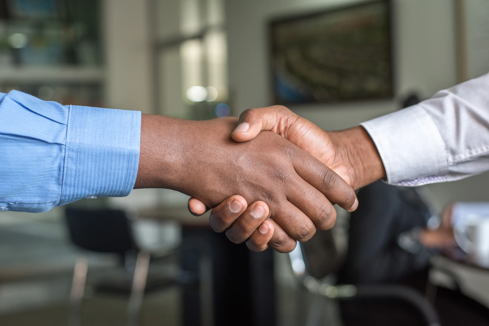 Two business people shaking hands across a meeting table