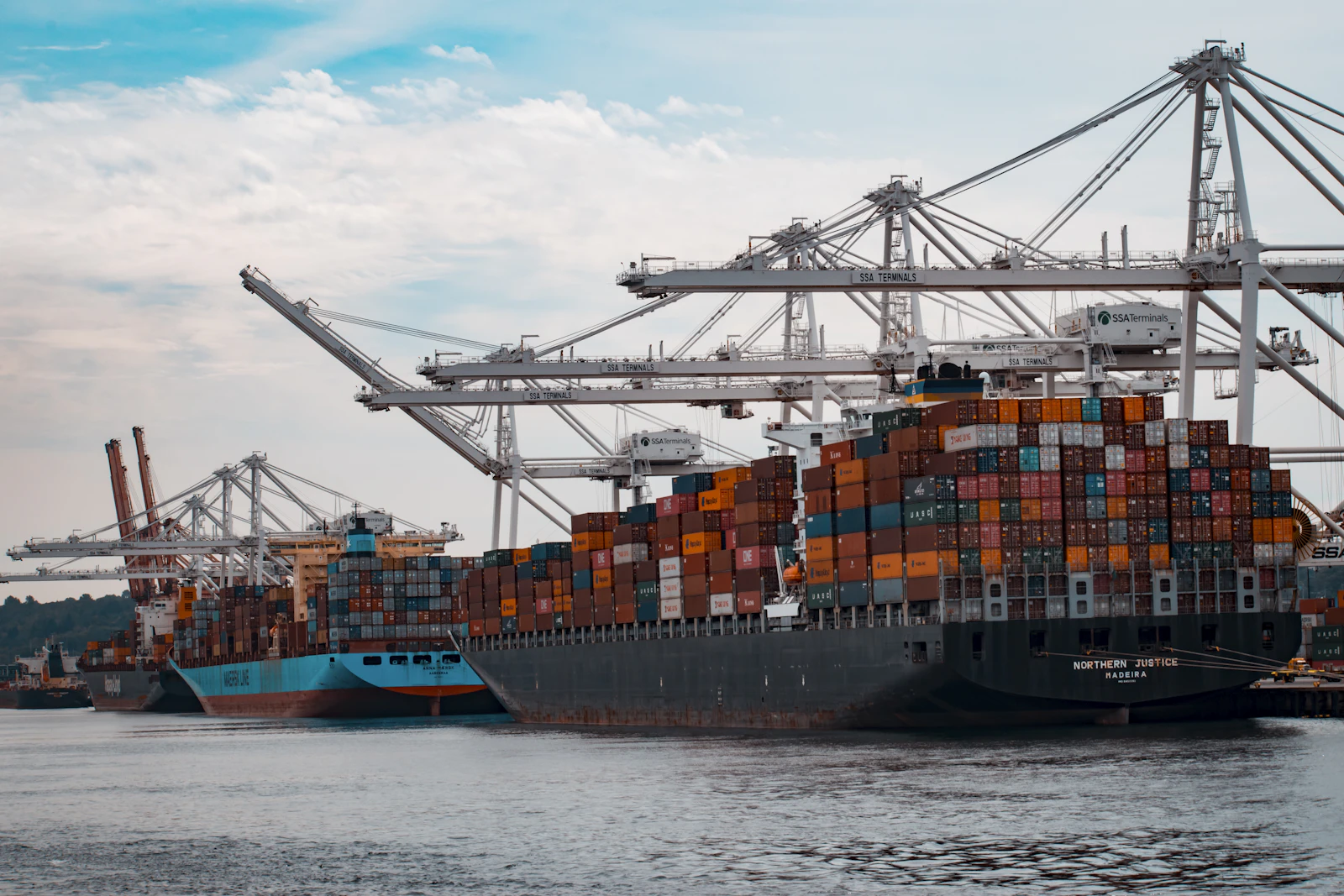 Container ships being loaded under gantry cranes at berth
